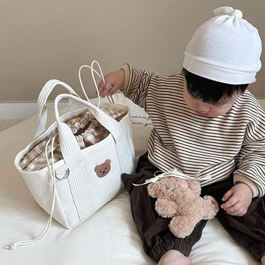 Bébé assis avec sac a langer et petit ourson
