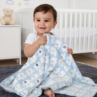 Bébé assis dans sa chambre tenant sa couverture bebe coton bio bleue.