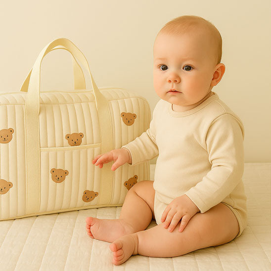 Bébé assis prêt de son sac a langer bebe de maternité.