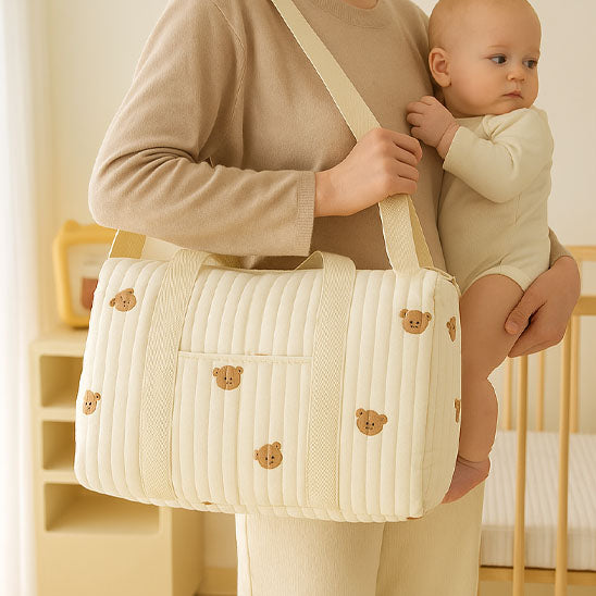 Bébé dans les bras de maman portant sac a langer bebe ourson