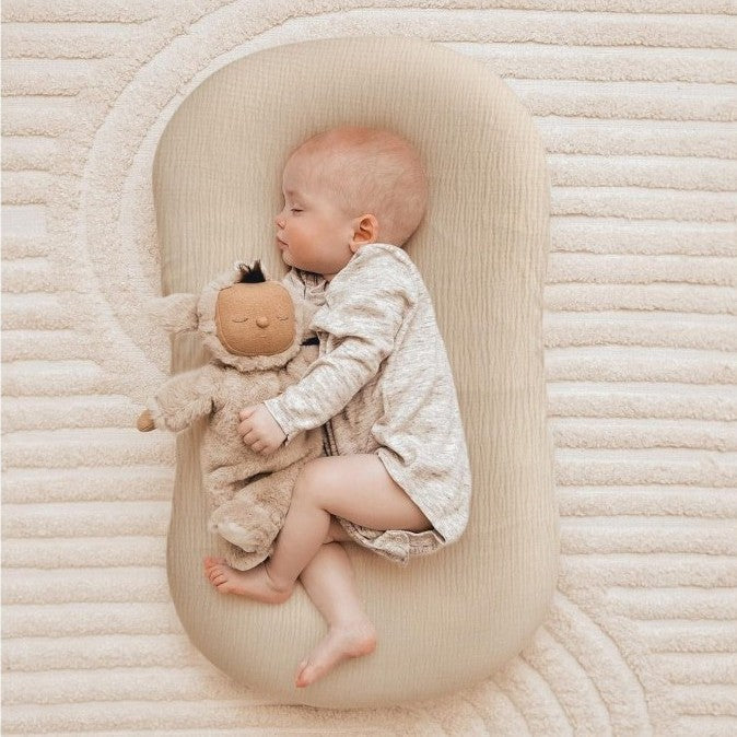 Bébé endormi sur coussin bébé beige confortable.