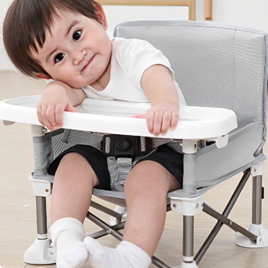 Bébé espiègle dans chaise haute bébé d'appoint