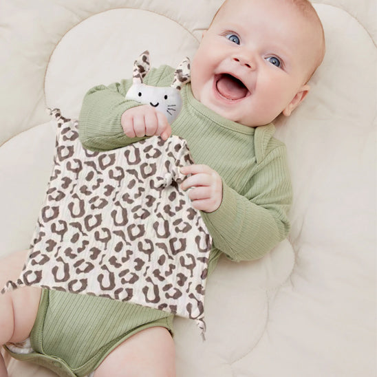 Bébé joyeux serrant doudou plat motifs léopard