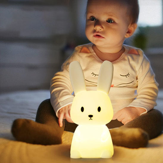 Bébé mignon assis avec veilleuse lapin tactile