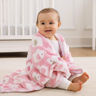 Bébé porte sa couverture bebe rose sur ses épaules.