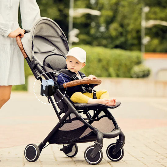 Enfant dans poussette au parc et support téléphone poussette
