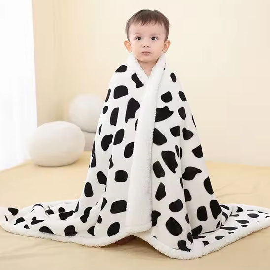 Enfant enroulé dans sa couverture bébé motif peau de vache.