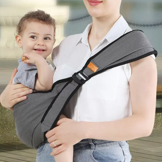 Enfant heureux assis dans son porte bebe hamac.