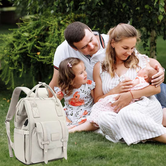 Famille assise au parc avec un sac à dos à langer spacieux.