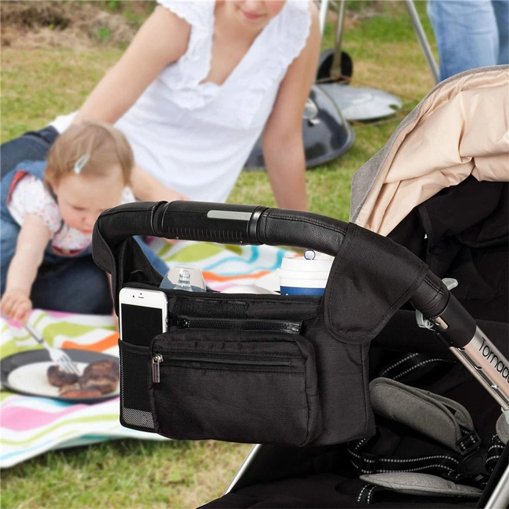 Famille en pique nique et sac a langer bebe accroché sur la poussette.