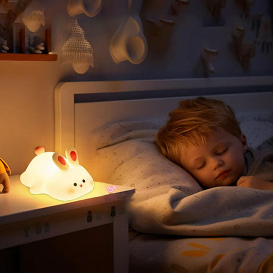 Garçon endormi avec veilleuse lapin sur table chevet