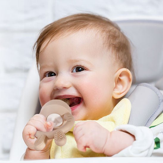 Bébé qui mordille sa grignoteuse bebe beige.