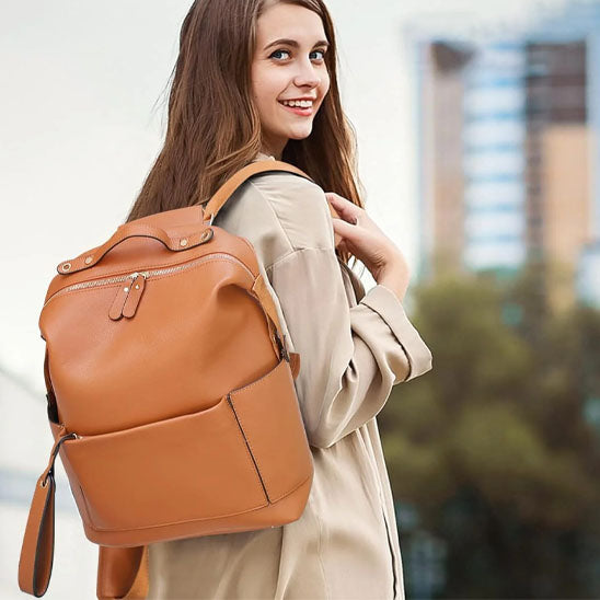 Jeune femme portant sac a dos a langer cuir tan