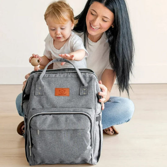 Maman assise avec bébé agrippant sac à dos à langer