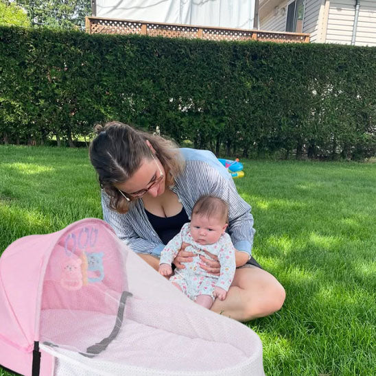 Maman et bébé assis dans le jardin avec couffin bebe