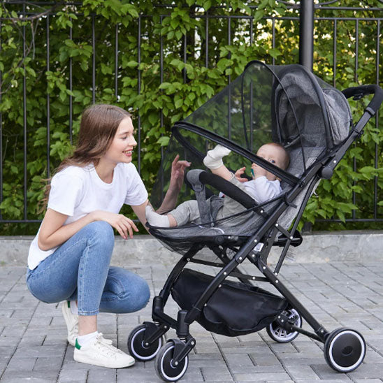 Maman regarde bébé dans la poussette protégé par moustiquaire bebe