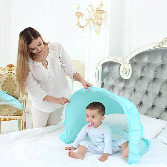 Maman soulève la moustiquaire lit bébé assis sur le lit