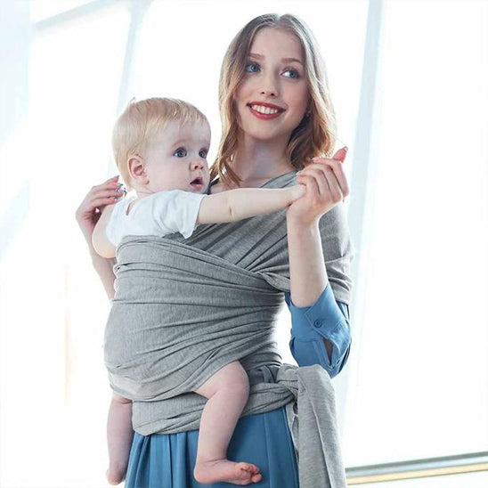 Maman tient mains de bébé dans écharpe de portage