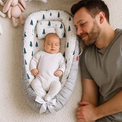 Papa allongé prêt de son nouveau-né dans son nid d ange portable.
