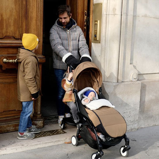 Papa en promenade avec les enfants et chancelière poussette
