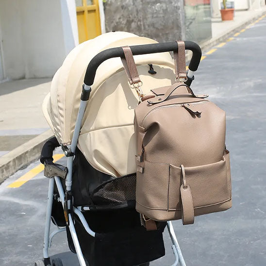 Sac a dos a langer cuir beige accroché poignée poussette