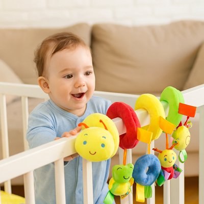 Spirale d'activité bébé enroulée sur les barreaux d'un parc bébé.