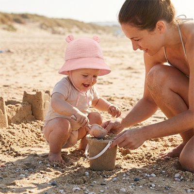 Bébé à la plage protégé par son bob bebe rose.