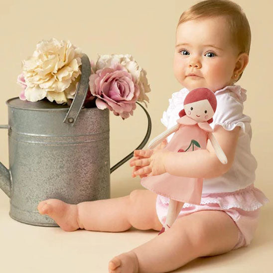 Bébé assis prêt arrosoir fleuri tient doudou bébé poupée