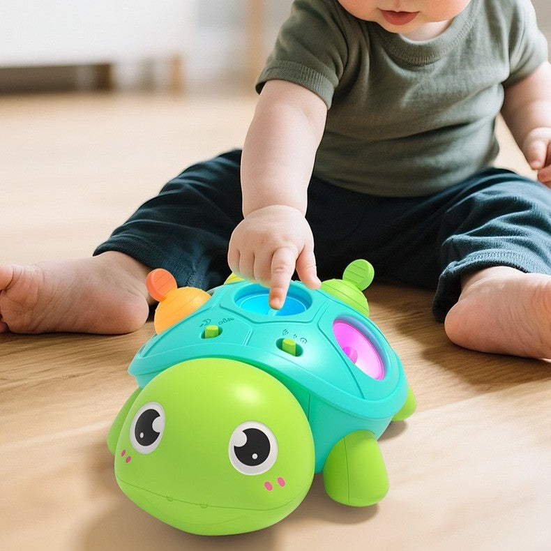 Bébé assis touhant une bulle en silicone de son jouet bebe tortue.