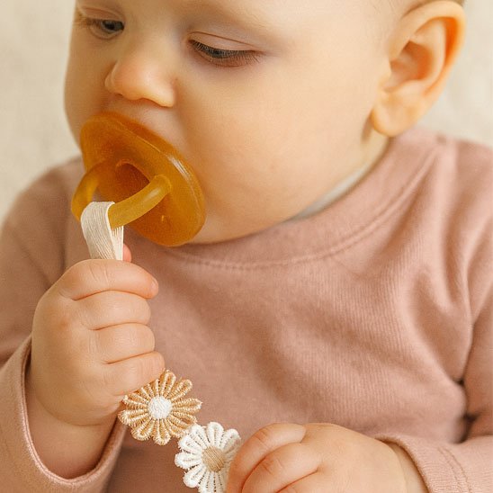 Bébé avec son attache tétine marguerite attachée sa sucette.