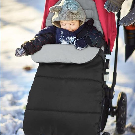 Bébé en promenade en hiver dans sa chanceliere poussette grise et noir.