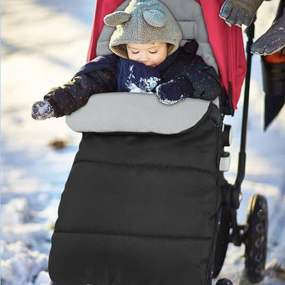 Bébé en promenade en hiver dans sa chanceliere poussette grise et noir.