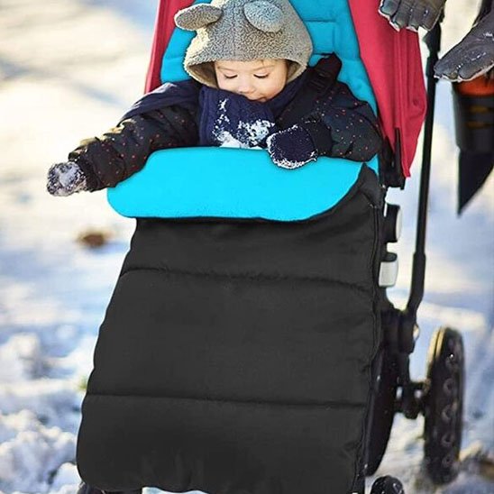 Bébé en promenade en hiver dans sa chanceliere poussette turquoise et noir.