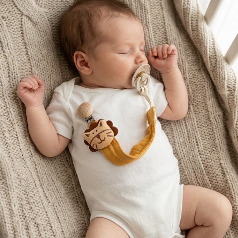 Bébé endormi avec son attache tetine tigre jaune.