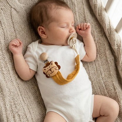 Bébé endormi avec son attache tetine tigre jaune.