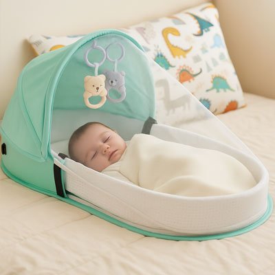 Bébé endormi sur le grand lit dans son lit bebe de voyage vert.