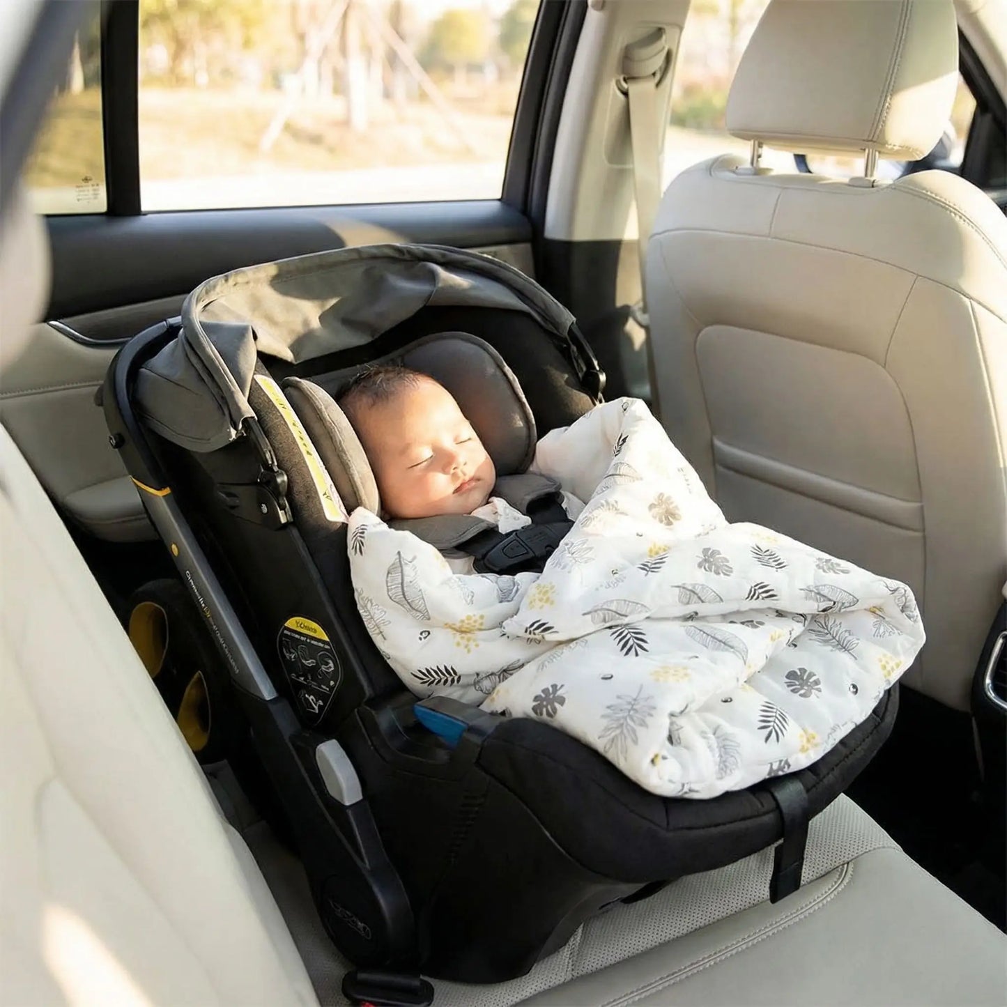 Bébé endormie dans nid d'ange siege auto motifs feuilles.