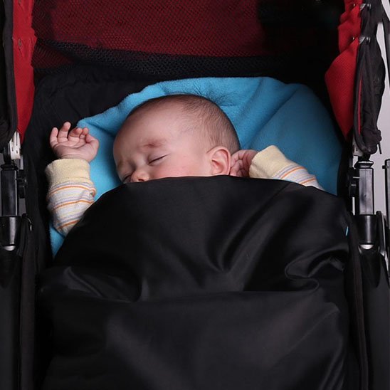 Bébé endormie dans sa chanceliere poussette en polaire thermique confortable.