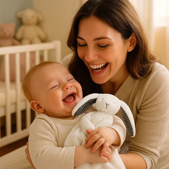 Bébé et maman rigolent ensemble avec son doudou lapin blanc.