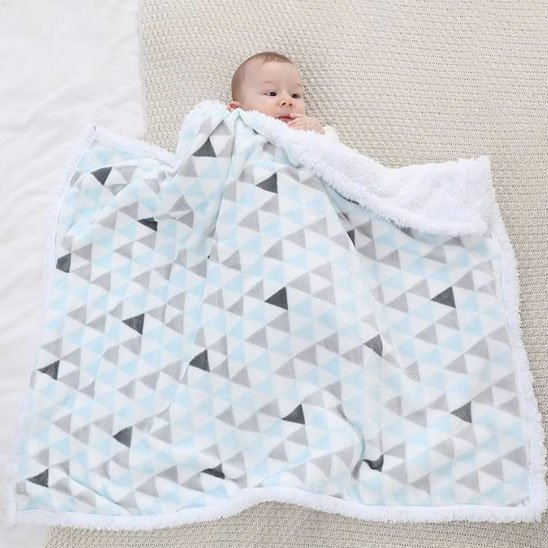 Bébé étendu au sol avec sa couverture polaire moelleuse et moderne.