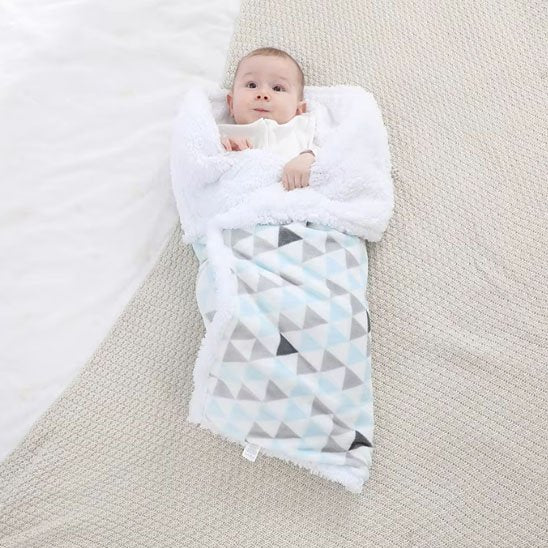 Bébé étendu au sol enroulé dans sa couverture polaire bleue.