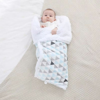 Bébé étendu au sol enroulé dans sa couverture polaire bleue.