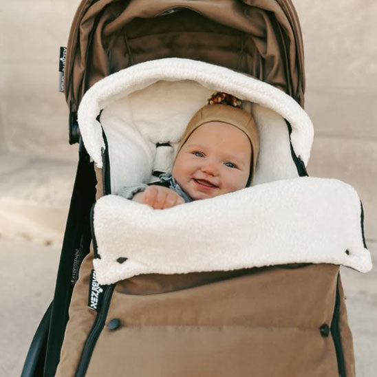 Bébé heureux dans chancelière poussette caramel