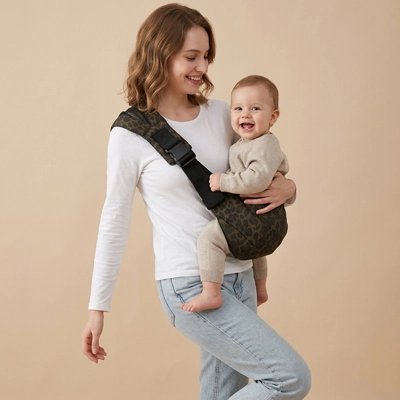Bébé heureux dans son porte bébé léopard marron en coton.