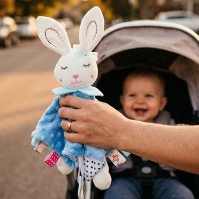 Bébé heureux de recevoir son doudou lapin bleu.