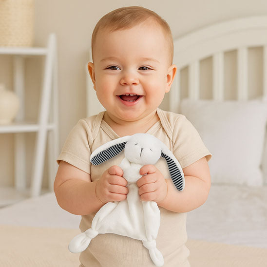 Bébé heureux en tenant son compagnon doudou lapin.