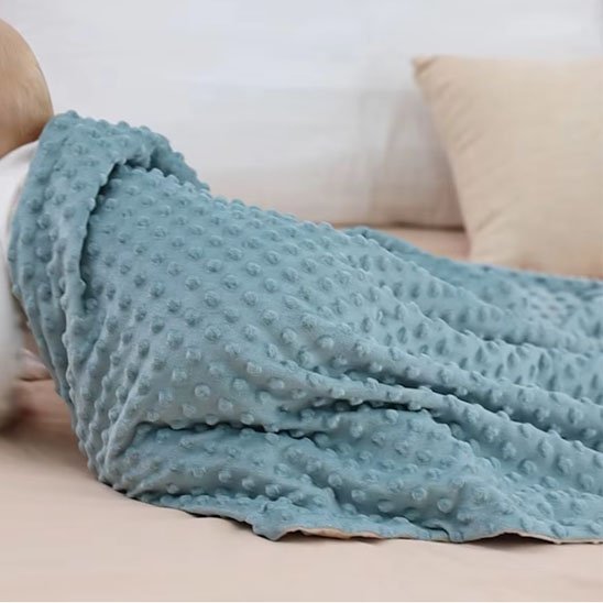 Bébé rampant avec sa couverture bebe bleue sur le dos.