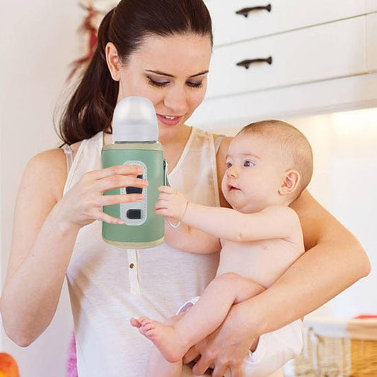 Maman tenant bébé et son chauffe biberon nomade compact.