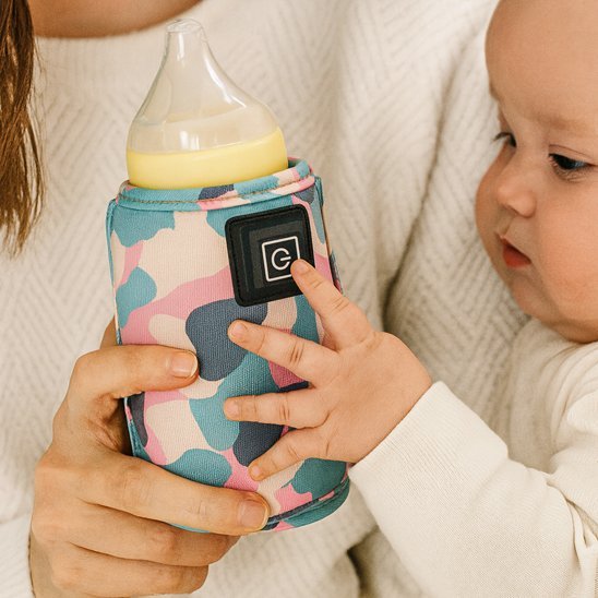 Bébé qui touche son chauffe biberon portable.