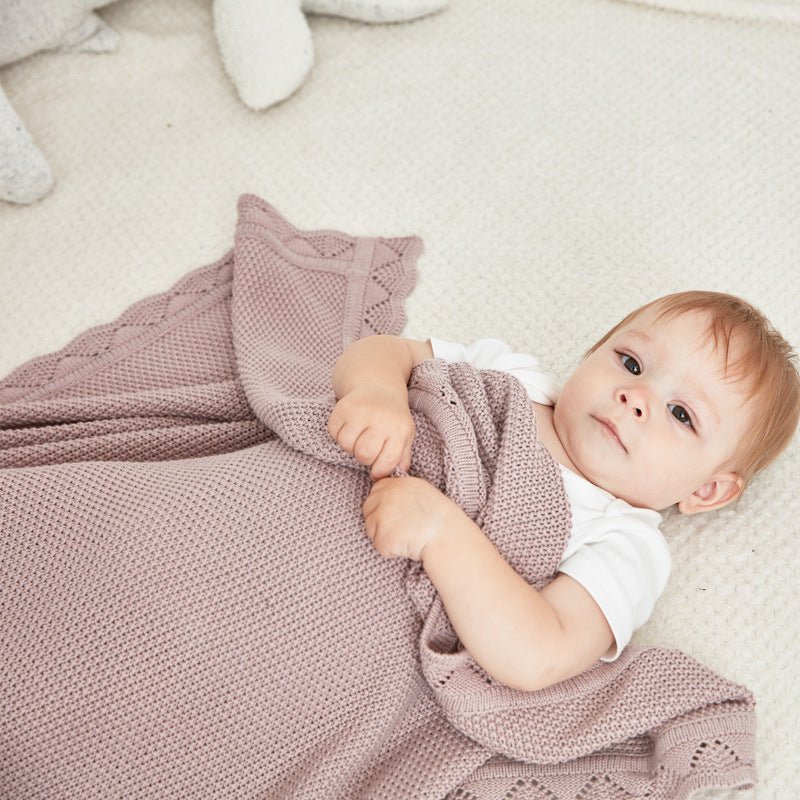 Bébé couché avec sa couverture bebe en tricot